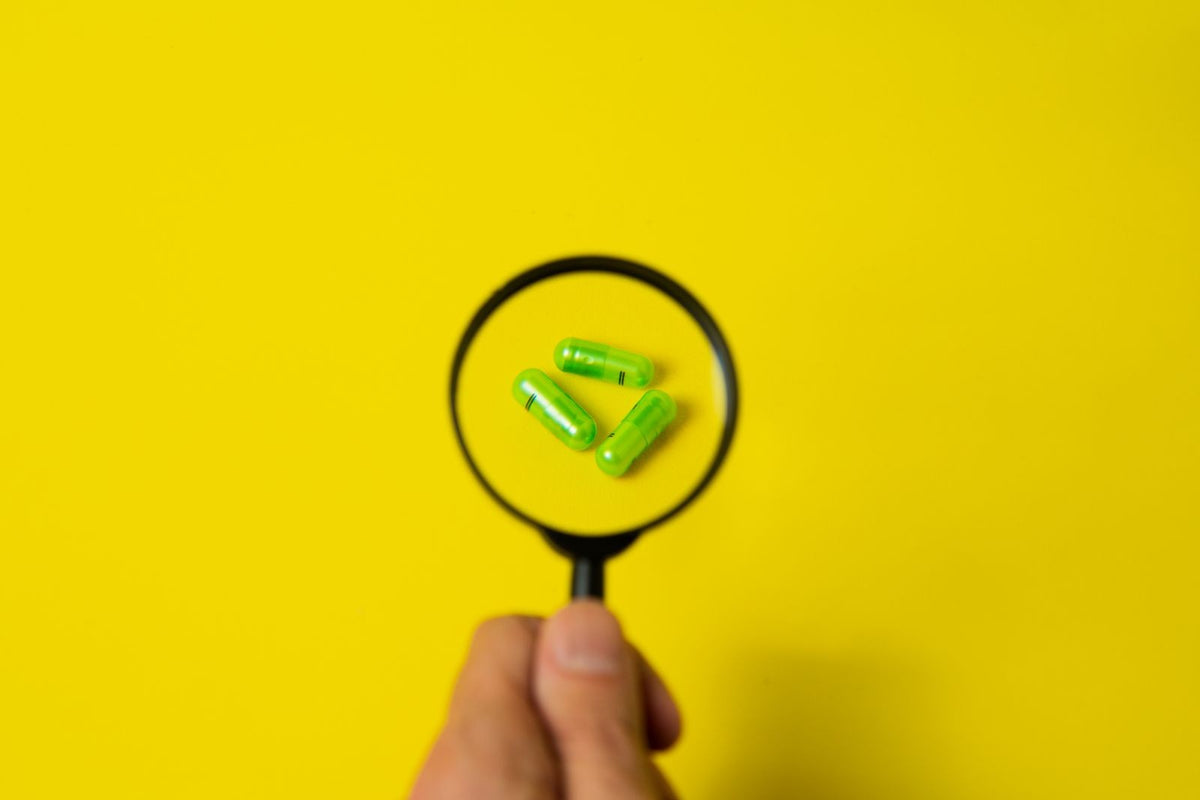 Magnifying glass over supplement capsules, for learning how to read curcumin product information carefully