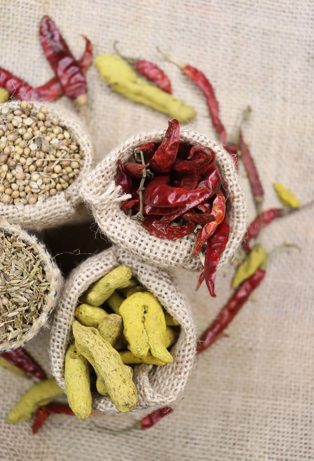 Assorted spices including turmeric arranged in burlap sacks on linen, for an educational look at common turmeric and curcumin myths