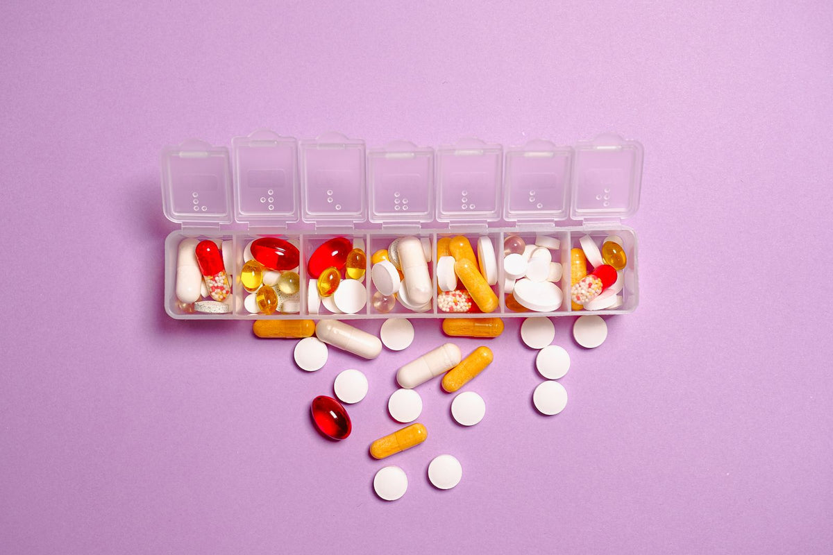 Assorted supplement capsules and tablets in a weekly organizer on a purple surface, for comparing forms with a simple evaluation framework